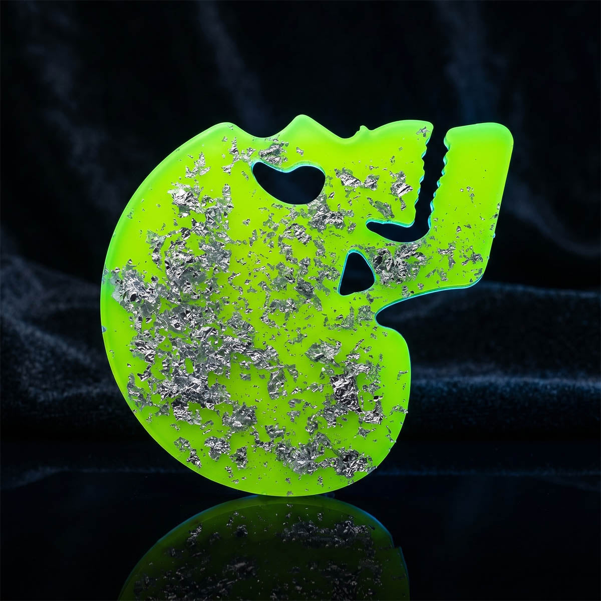 Neon green skull coaster with glitter on a black background.