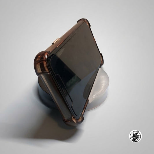 A dark brown translucent protective phone case with a black screen protector, shown resting on a clear circular stand against a light gray background.