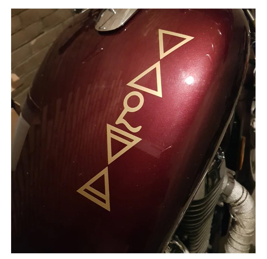 Close-up of a motorcycle fuel tank with gold ghouls symbols on a red background