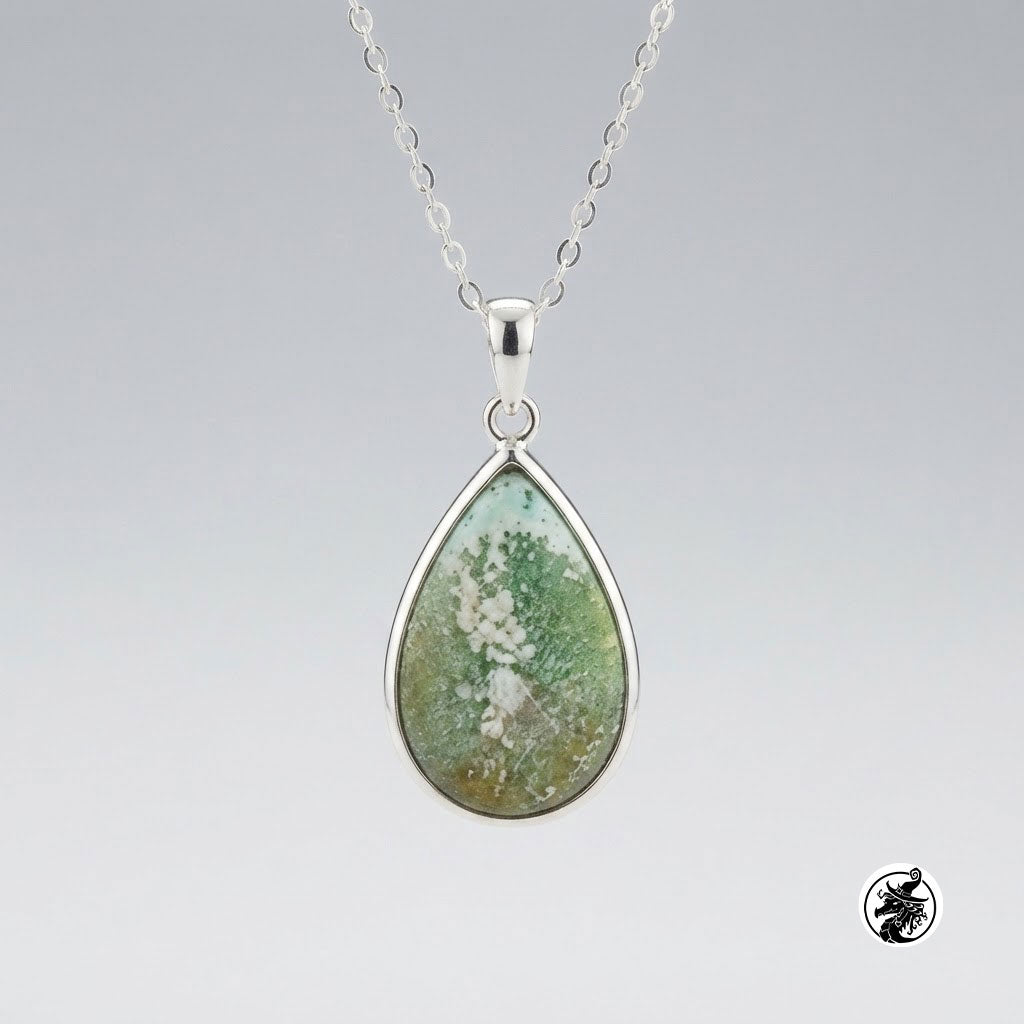 A silver teardrop pendant necklace featuring a natural mossy green and white mineral inlay, suspended from a delicate silver chain against a neutral gray gradient background.