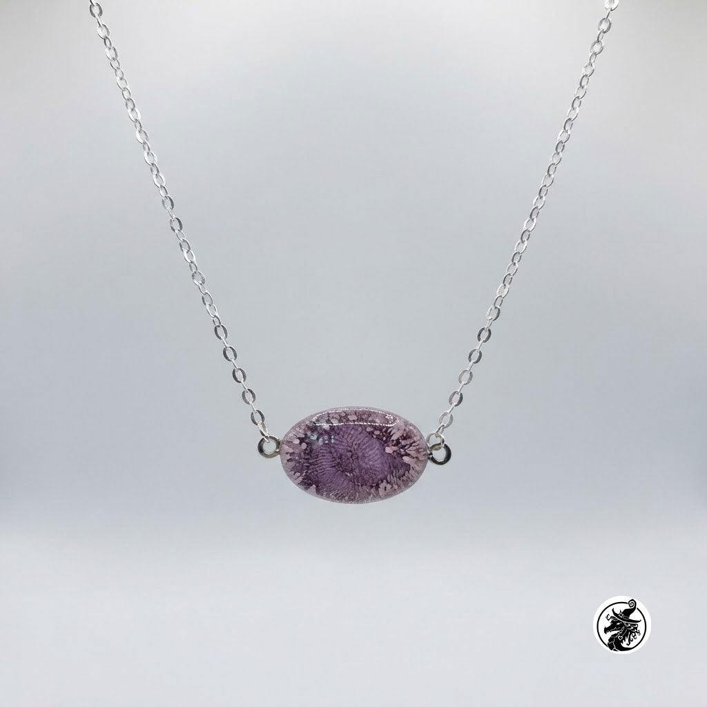 A silver chain necklace featuring an oval purple stone pendant with a textured, crackled surface, displayed against a neutral light gray background.