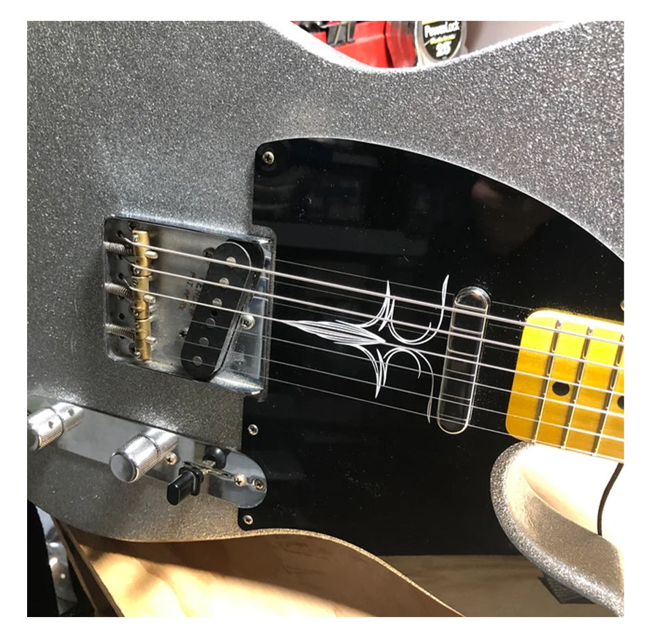 Close-up of a guitar with a glittery body and black pickguard with white pinstripe decal