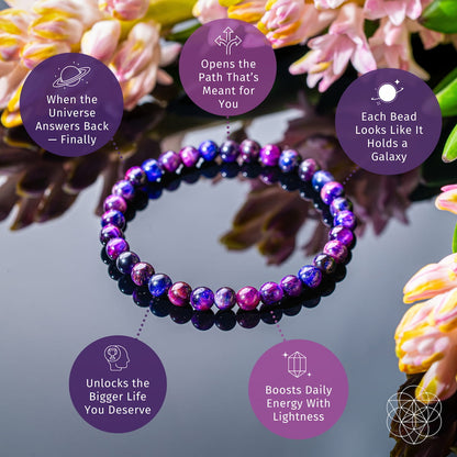 The Destiny Activator - All-Galaxy Tiger’s Eye Bracelet | 6mm by Conscious Items lies on a shiny surface with flowers nearby. Text bubbles show benefits like unlocking cosmic destiny and boosting energy. Each bead looks like a miniature galaxy.