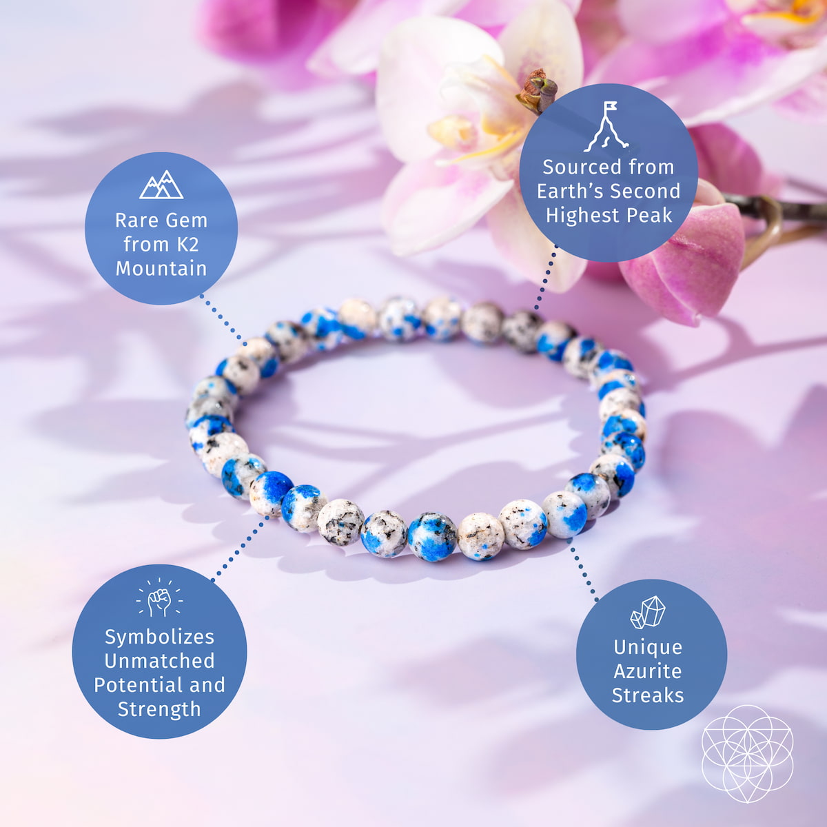 A Rare K2 Stone Bracelet of Spiritual Adventure | 6mm from Conscious Items, with striking azurite streaks and granite origins, rests on a pastel surface with pink orchids, symbolizing strength and Earth’s second highest peak.