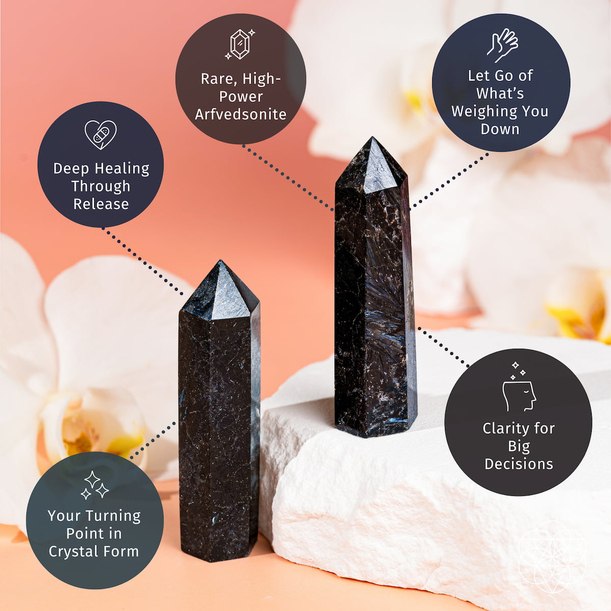 Two "This Is Your Breakthrough – Rare Arfvedsonite Point" crystals by Conscious Items stand on a white stone, surrounded by white flowers, symbolizing deep healing energy, clarity in decisions, and the release of burdens.