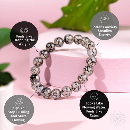 The Calm in the Chaos - River Agate Bracelet by Conscious Items features round beads with a black and white marbled pattern on a pink base. Four captions highlight its stress-relief benefits, set against leaf and wave graphics.