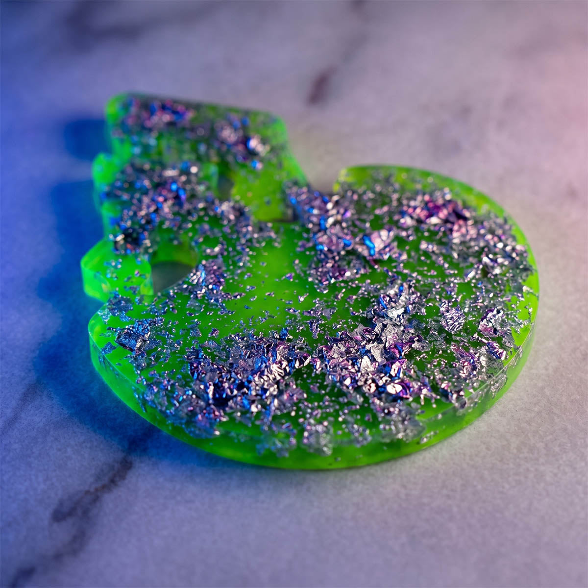 Green skull-shaped object with glitter on a marble surface
