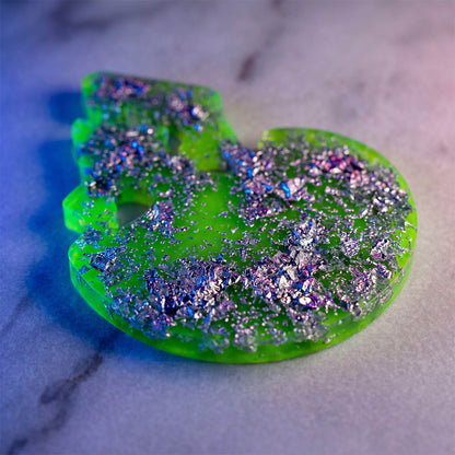 Green skull-shaped object with glitter on a marble surface