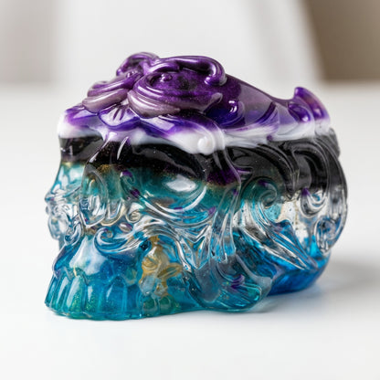 The Dragonsteins Monster Resin Skull by GorgeousDragon Designs LLC. features intricate swirling patterns in blue, green, black, and purple—a unique desk organizer made from recycled artisan resin.