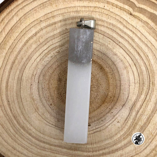 A rectangular translucent pendant or candle holder with a silver metal cap, placed on a circular wood slice background.