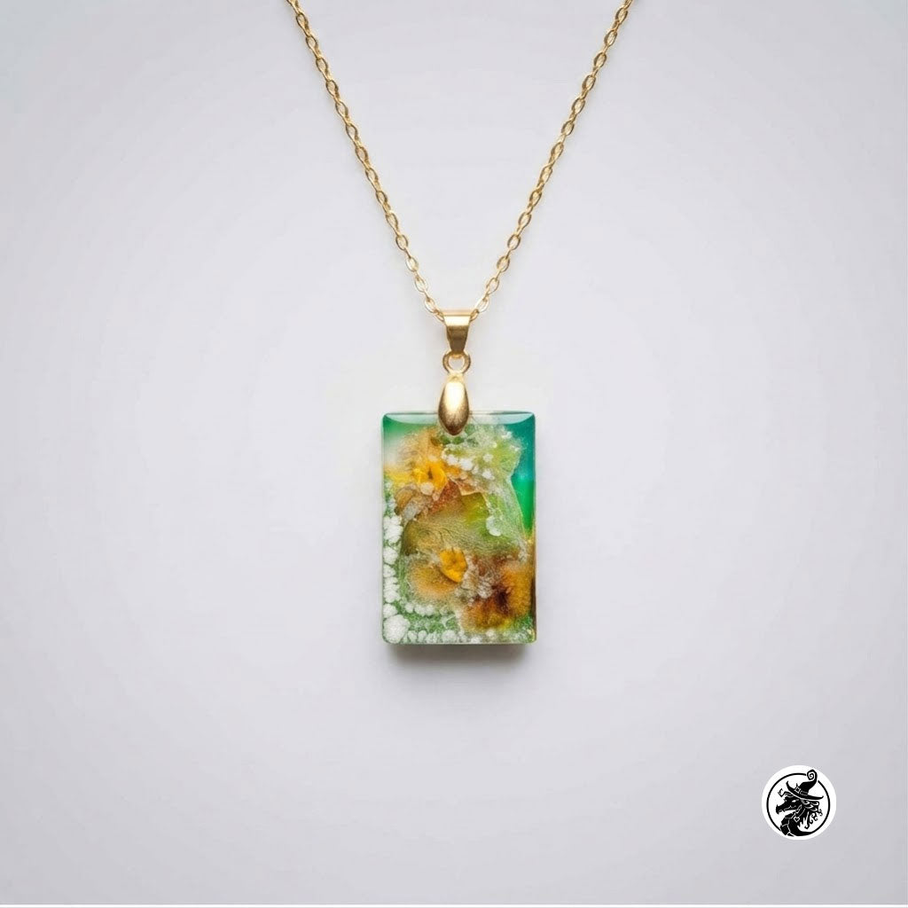 A gold chain necklace with a rectangular pendant featuring a green and yellow floral or mineral-like pattern, shown on a light gray background.