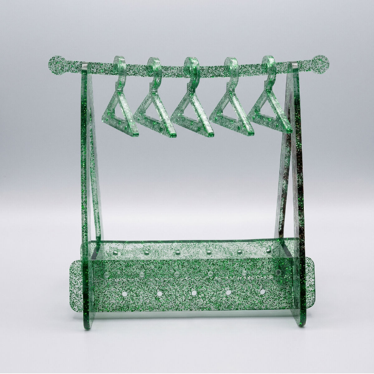 Green glittery jewelry stand with multiple hooks on a light gray background