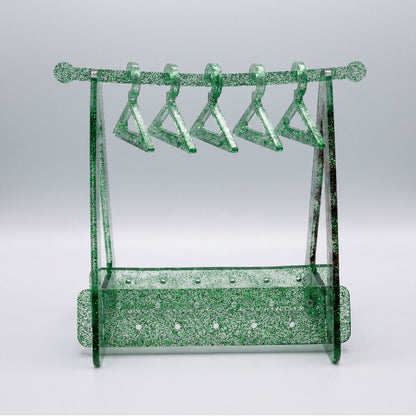Green glittery jewelry stand with multiple hooks on a light gray background