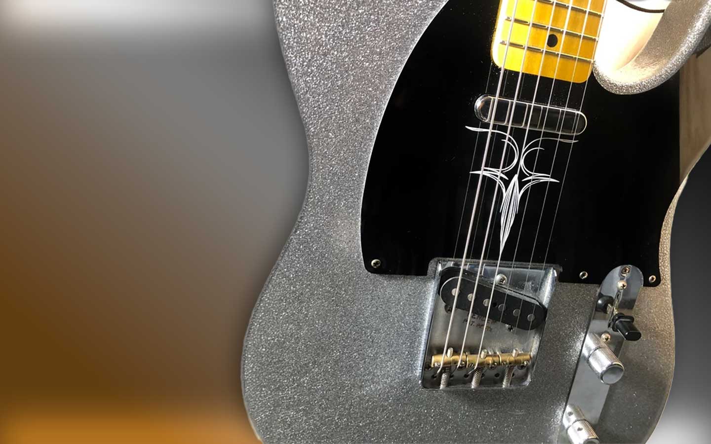 Close-up of a silver electric guitar with a blurred background
