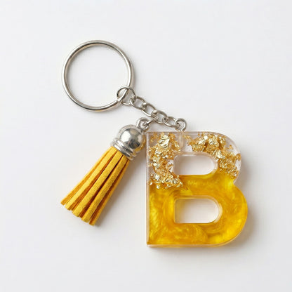 Keychain with yellow letter 'B' and tassel on a white background