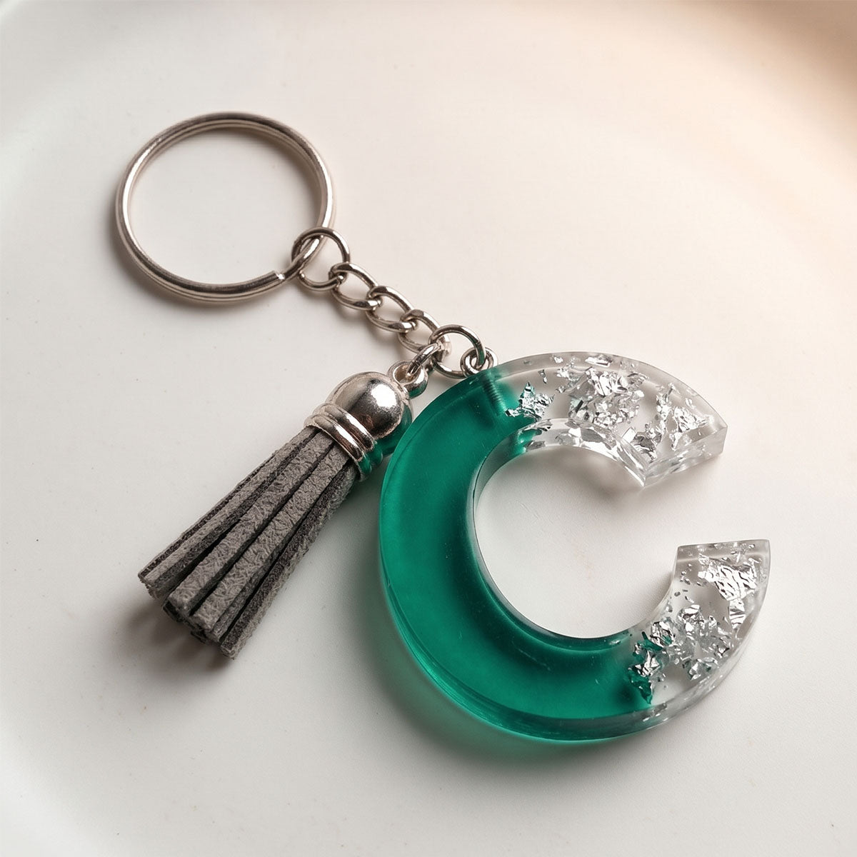 Keychain with green crescent moon design and tassel on a white background