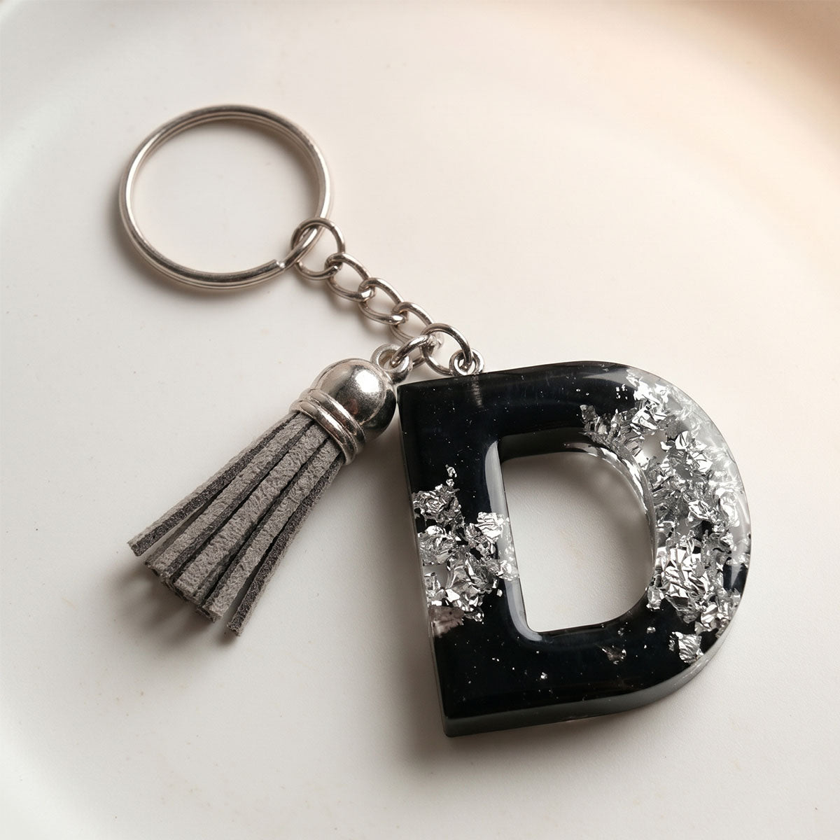 Keychain with letter 'D' and tassel on a light background