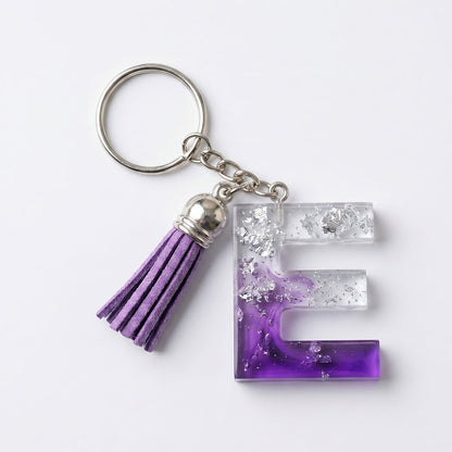 Keychain with letter 'E' and purple tassel on a white background