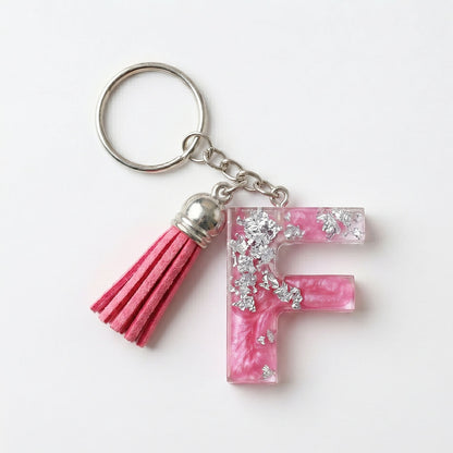 Keychain with pink letter 'F' and tassel on a white background