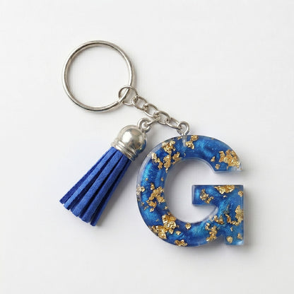 Keychain with blue letter 'G' and tassel on a white background