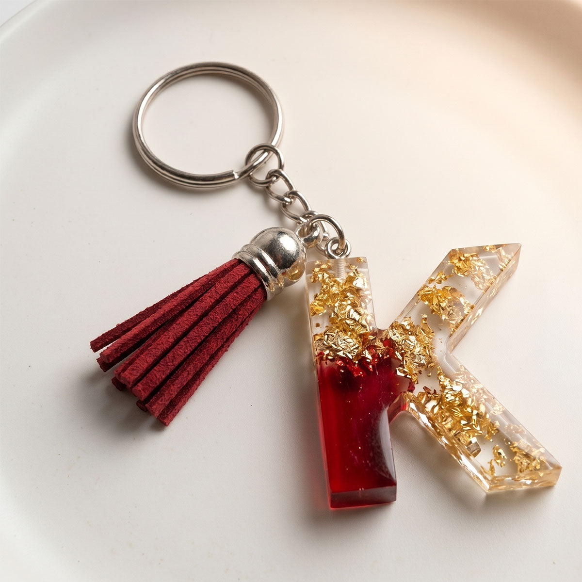 Keychain with red tassel and letter 'K' charm on a white background