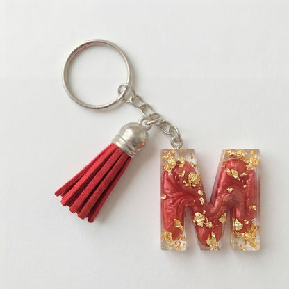 Keychain with red letter 'M' and tassel on a white background