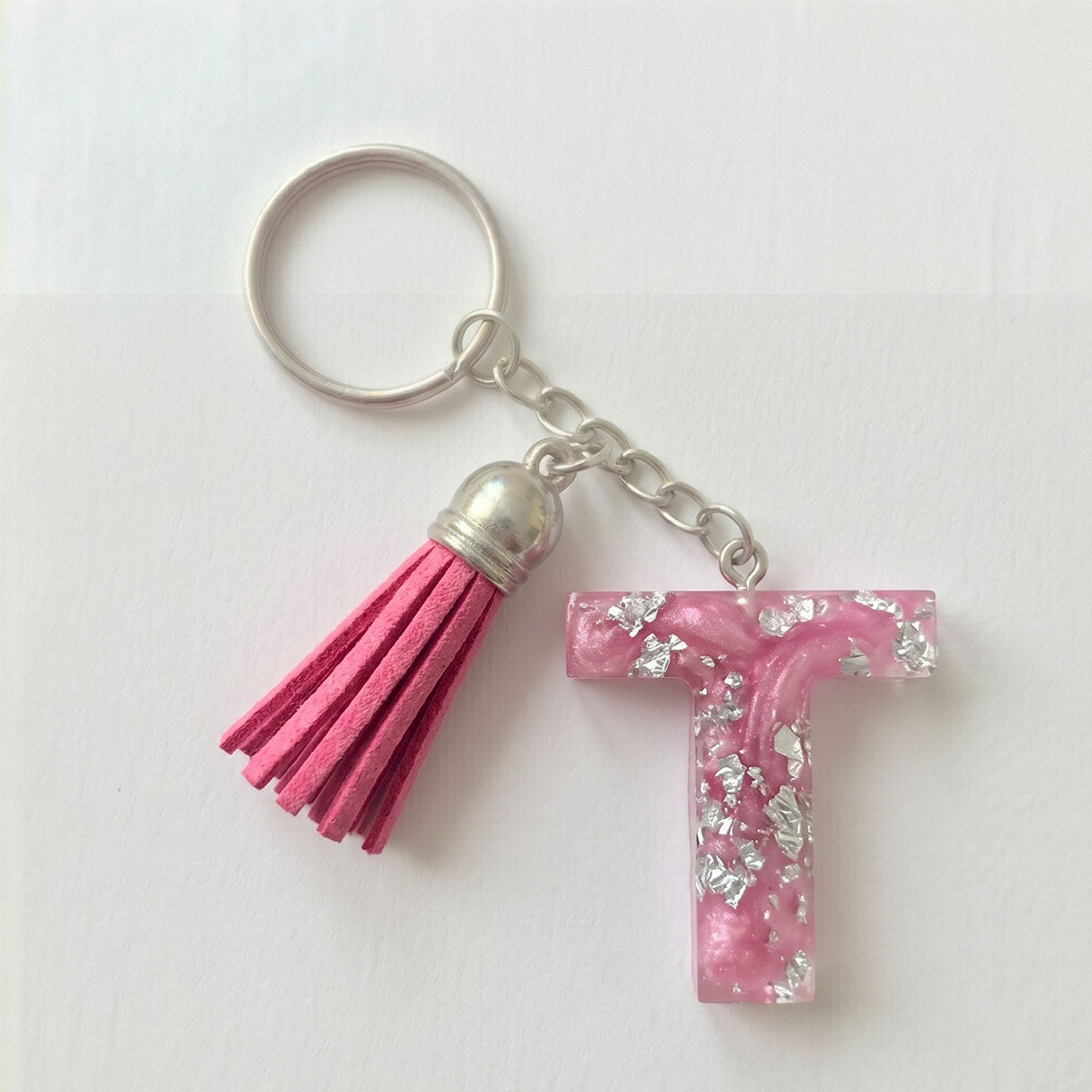 Keychain with pink tassel and letter 'T' charm on a white background