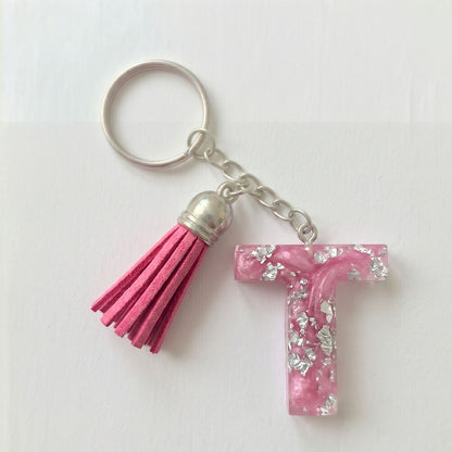 Keychain with pink tassel and letter 'T' charm on a white background