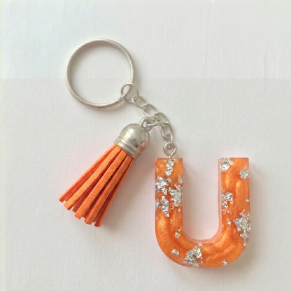 Keychain with orange letter 'U' and tassel on a white background