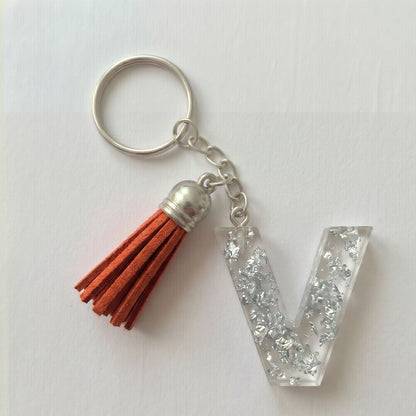 Keychain with orange tassel and letter 'V' charm on a white background