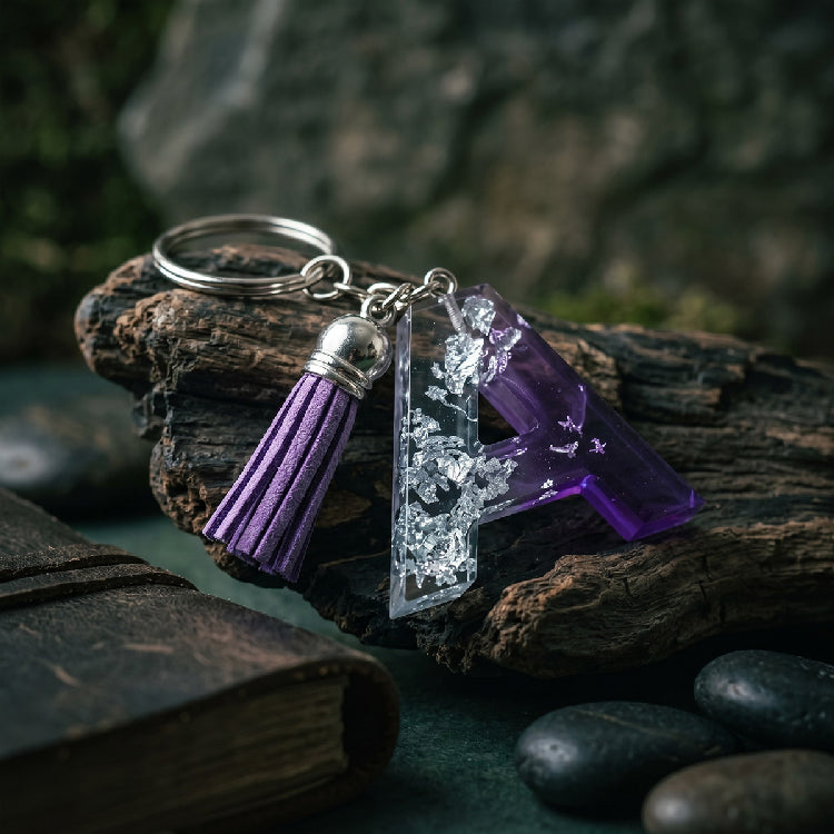 Keychain with purple tassel and crystal-like charm on a rock with a natural background