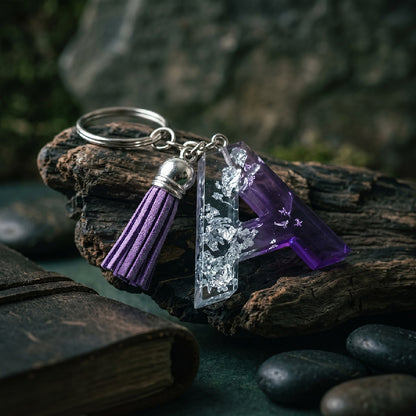 Keychain with purple tassel and crystal-like charm on a rock with a natural background