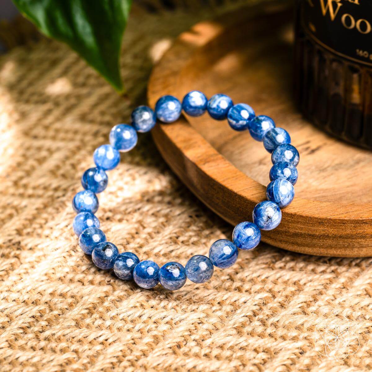 The My Truth, My Power – Rare Kyanite Bracelet by Conscious Items features shiny blue stones on a wooden tray with natural accents—ideal for throat chakra balance.
