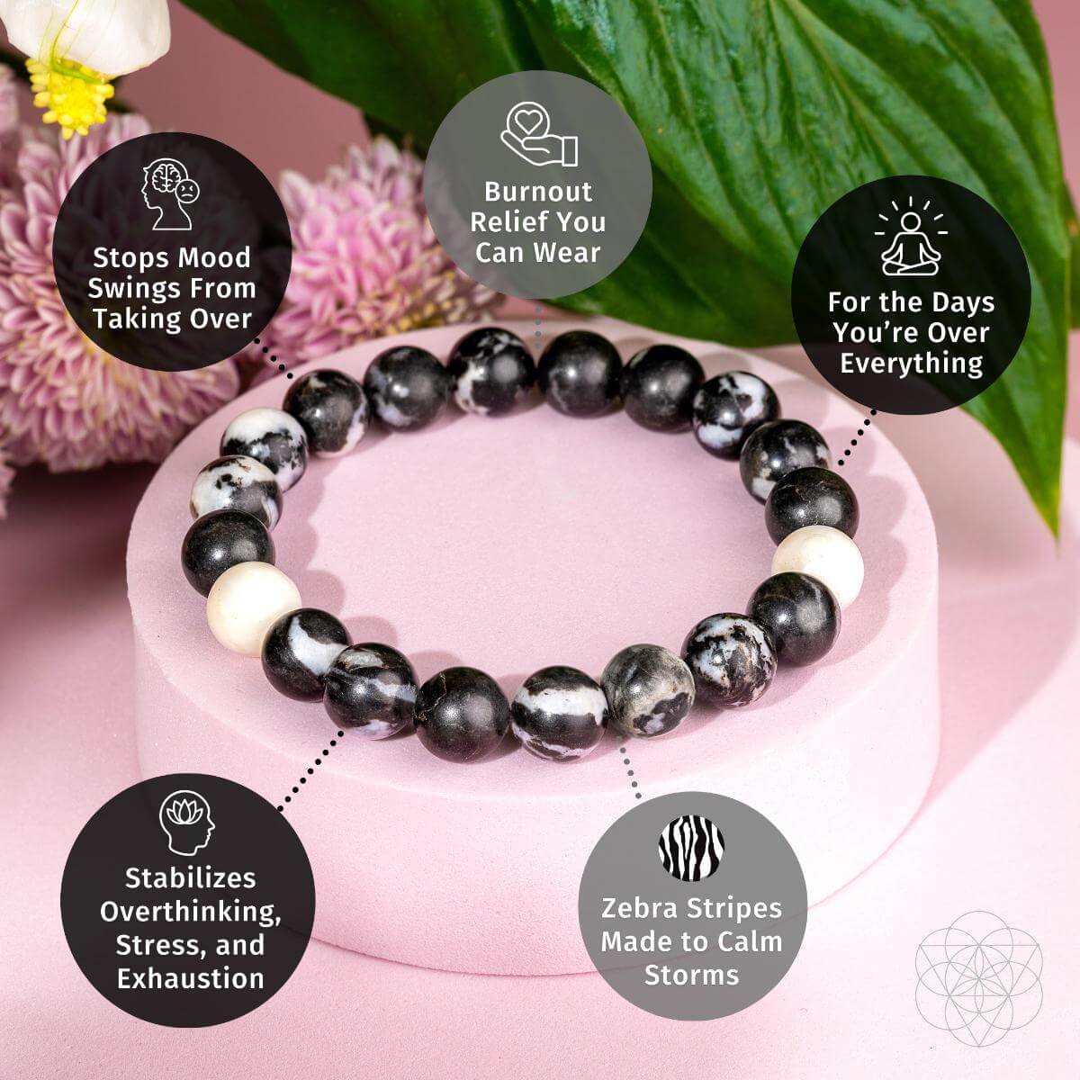 The Permission to Pause - The Zebra Jasper Bracelet by Conscious Items, shown on a pink surface with flowers, features five benefit bubbles: emotional balance, burnout relief, mood stabilization, calming effects, and more.