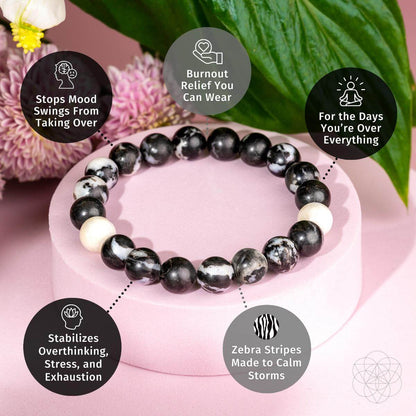 The Permission to Pause - The Zebra Jasper Bracelet by Conscious Items, shown on a pink surface with flowers, features five benefit bubbles: emotional balance, burnout relief, mood stabilization, calming effects, and more.