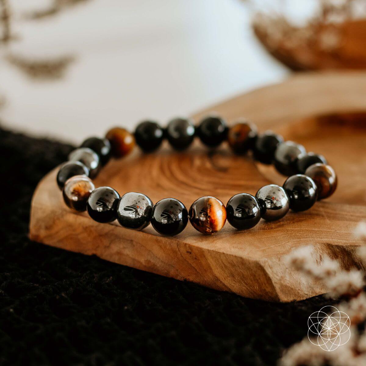 A Black Friday exclusive, the Sacred Healing & Protection Trio by Conscious Items features shiny black and brown stones on a carved wooden dish with a soft-focus background and geometric logo in the lower right corner.