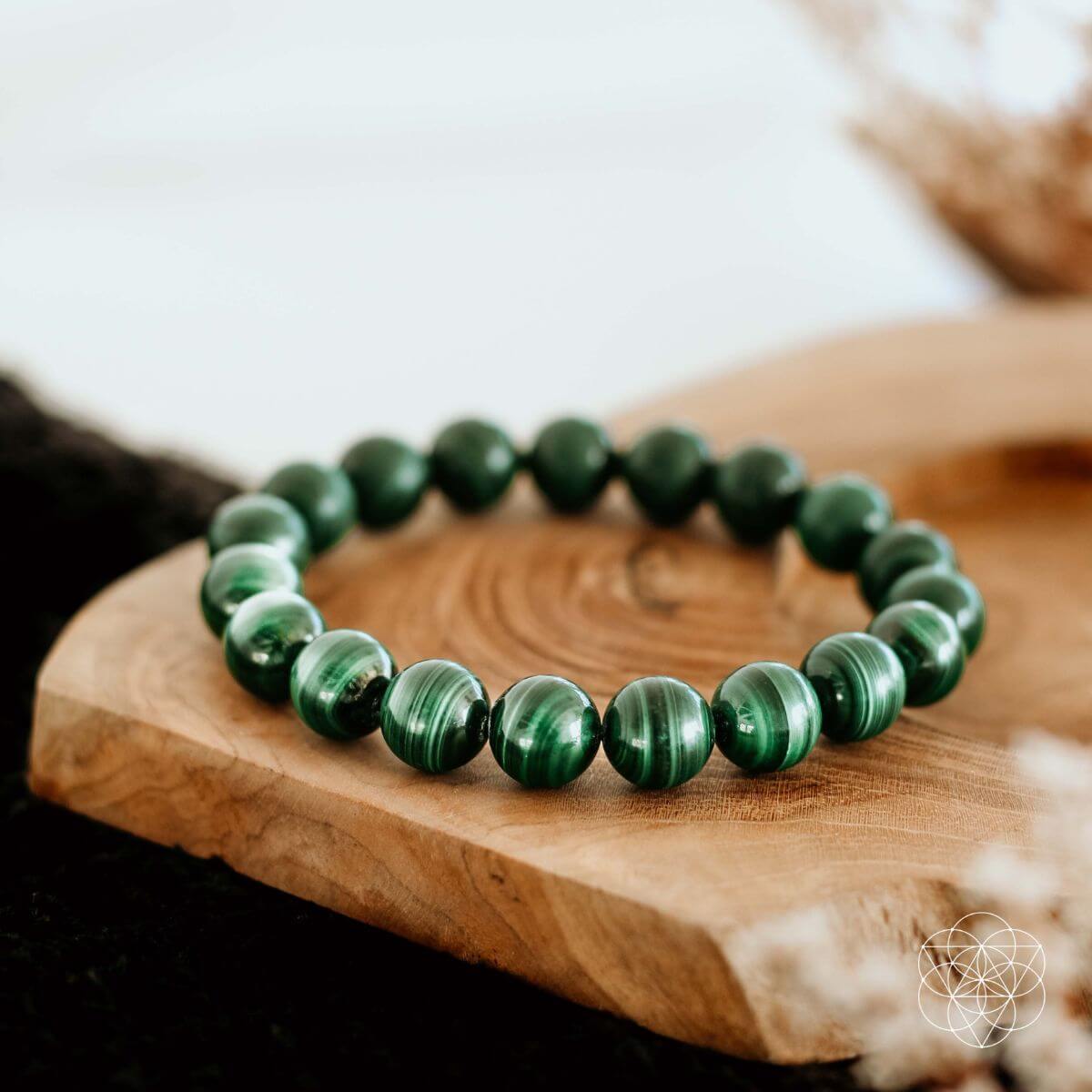 A Peace & Protection Bracelet from Conscious Items is shown on a smooth, light wooden surface with softly blurred decor in the background.