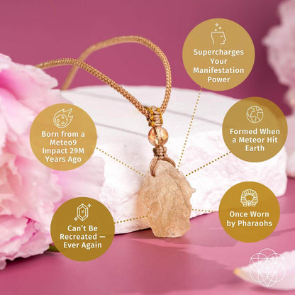 The Destiny Relic – Libyan Desert Glass Pendant by Conscious Items rests on a pink surface among flowers. Circular text bubbles reveal its rare meteor impact origin, unique manifestation benefits, and authentic Libyan Desert Glass material.