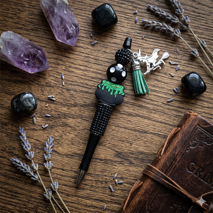 Decorative pen with charms on a wooden surface with crystals and lavender.